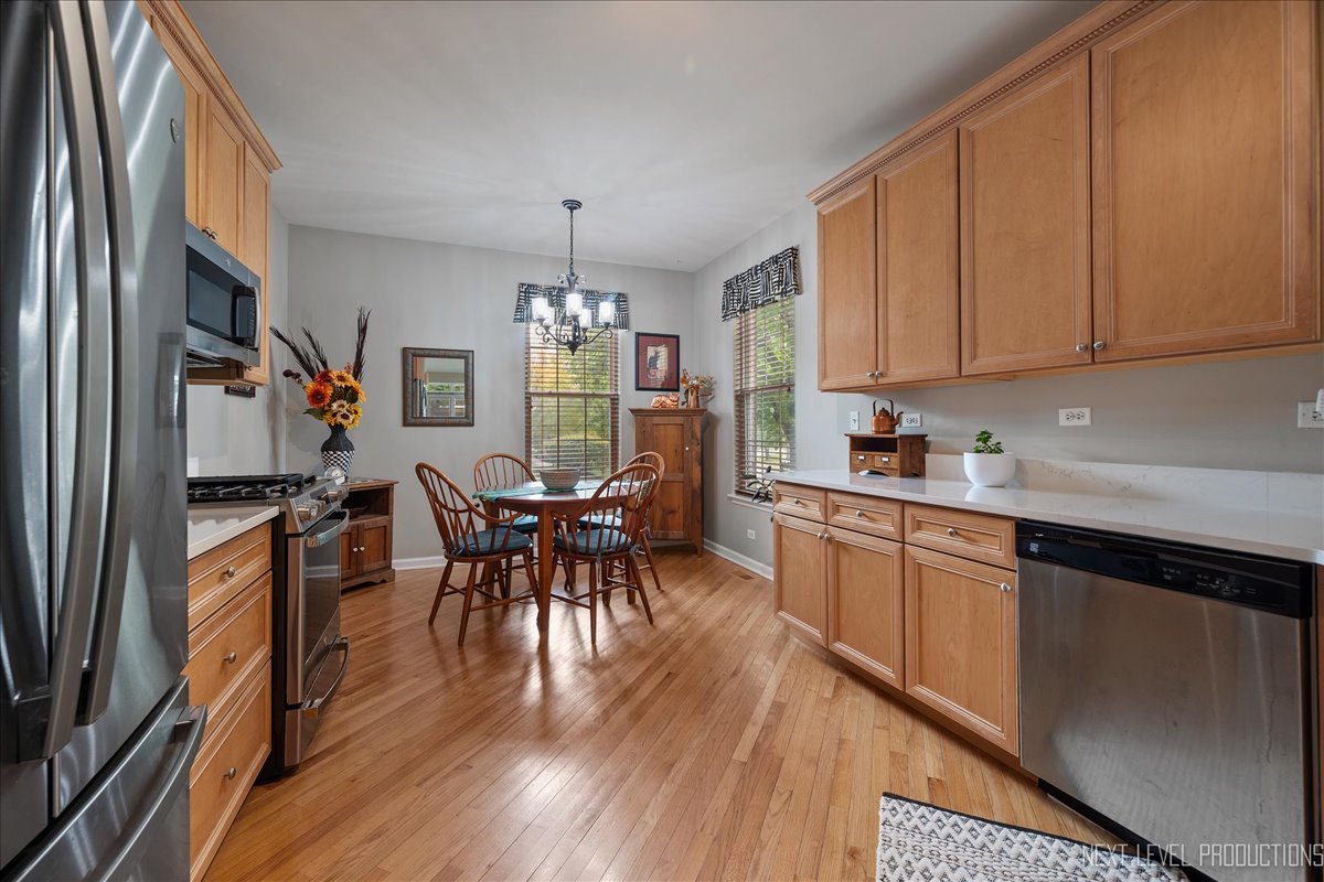 332 Wolcott Lane Batavia, IL 60510 - Photo 11 of 28 a open kitchen with stainless steel appliances granite countertop a stove a refrigerator a sink a dining table and chairs with wooden floor