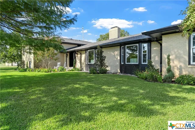 a view of house with backyard and outdoor seating