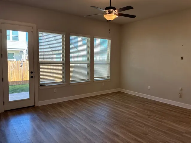 a view of an empty room with wooden floor and a window