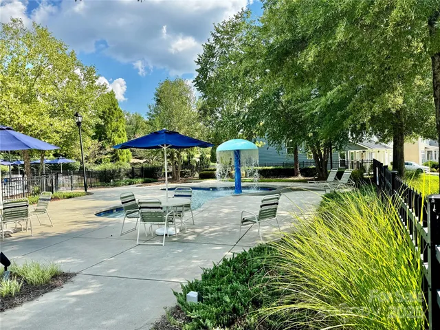 a view of swimming pool with outdoor seating and trees in the background