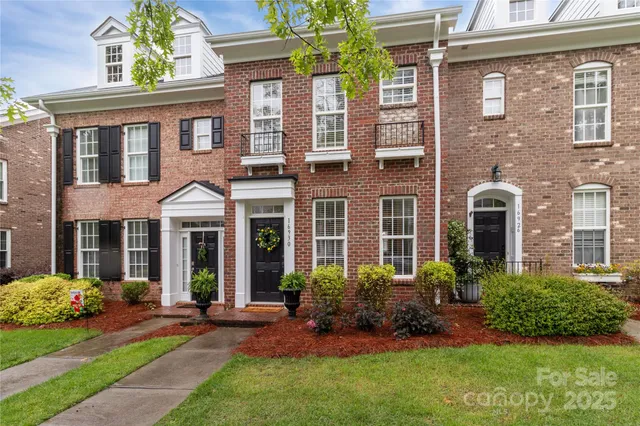 a view of a brick house with a yard and plants next to a yard