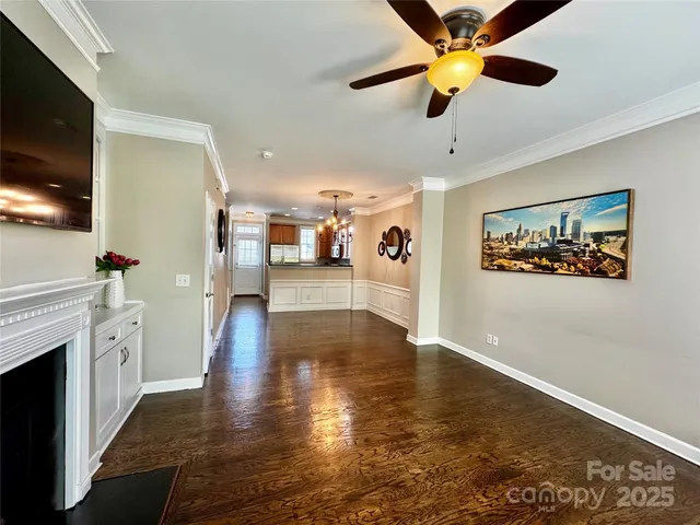 a view of a livingroom with a fireplace a chandelier fan and wooden floor