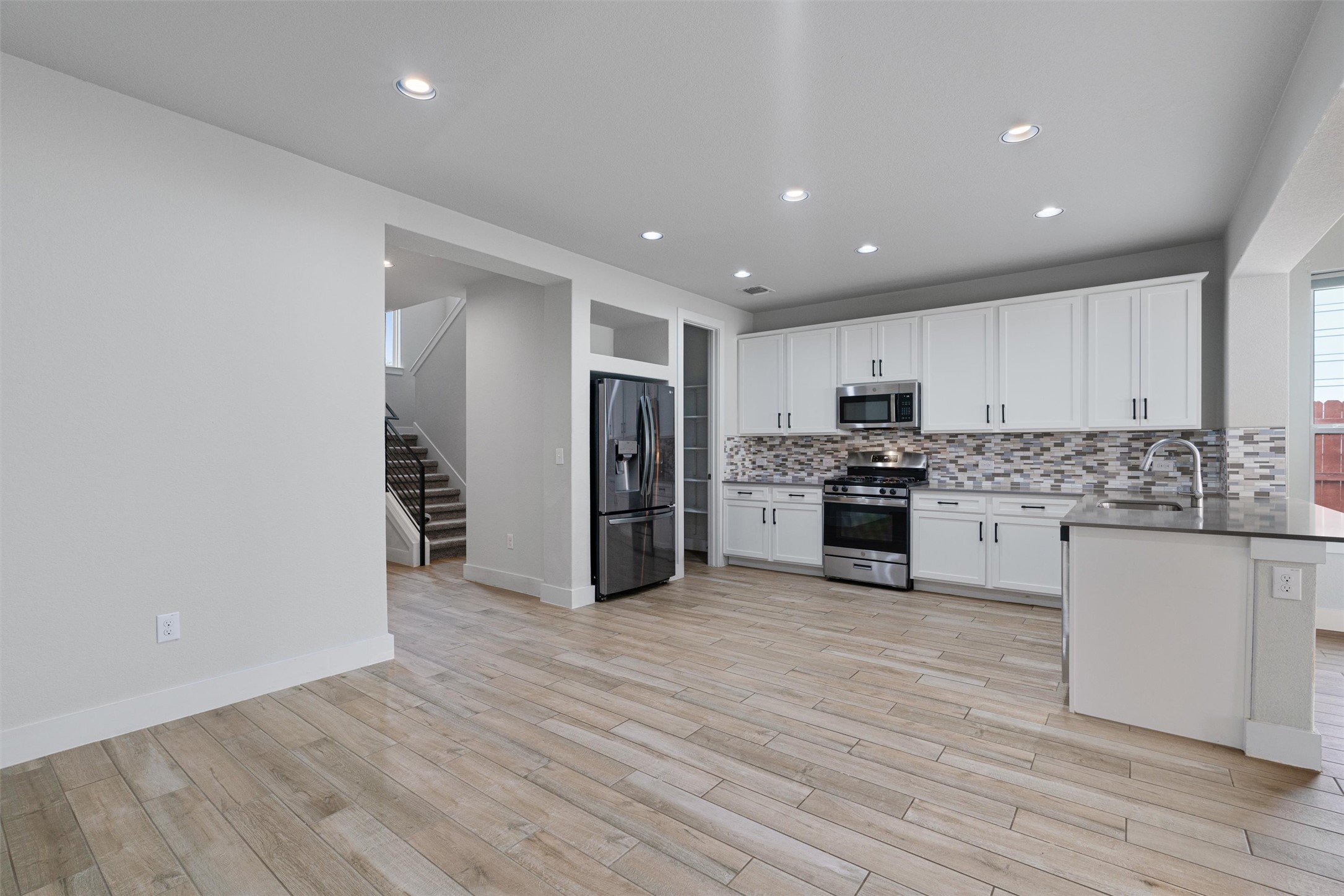11217 Charger Way Manor, TX 78653 - Photo 11 of 35 Kitchen featuring white cabinets, stainless steel appliances, a peninsula, recessed lighting, and decorative backsplash