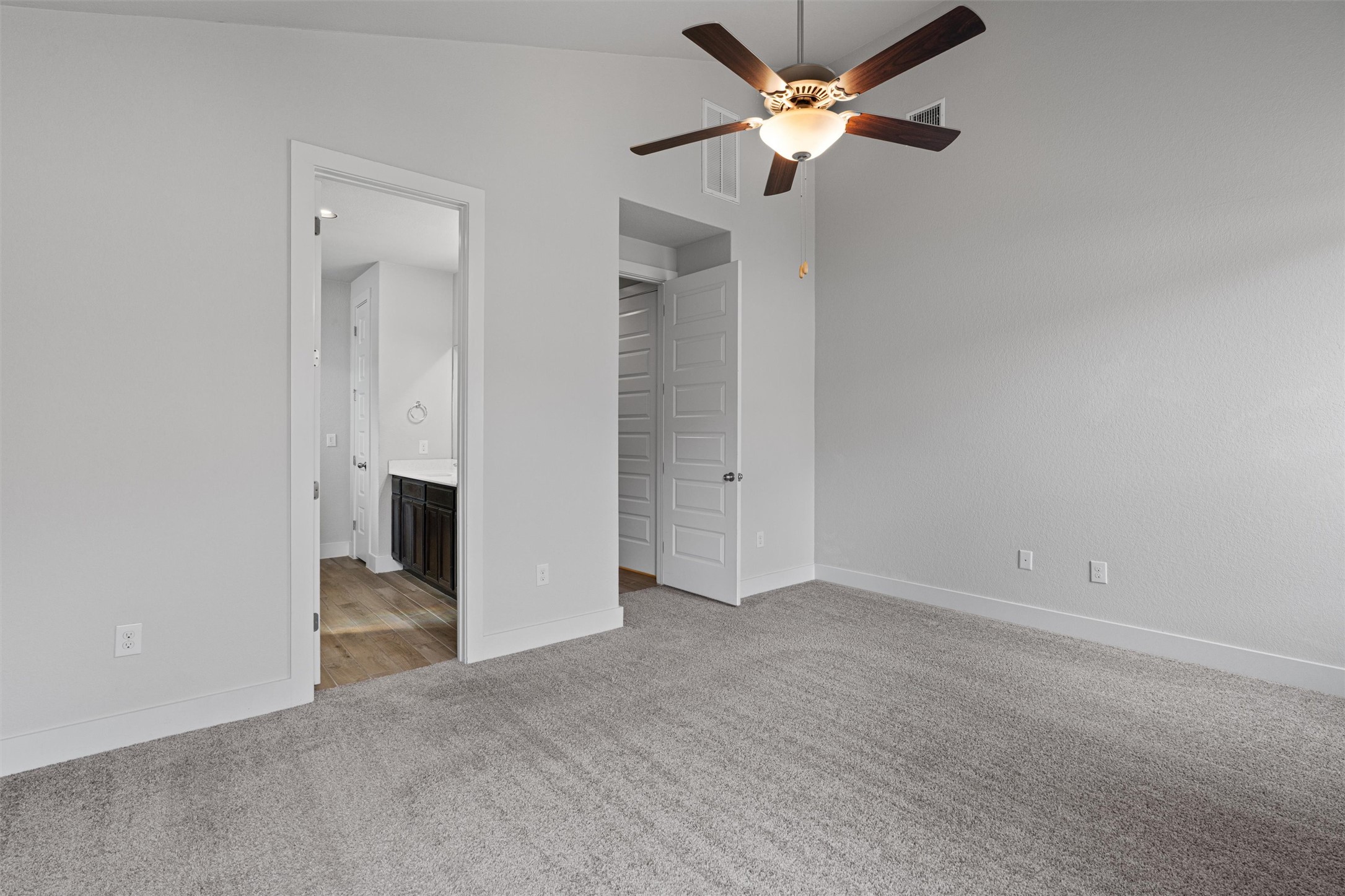 11217 Charger Way Manor, TX 78653 - Photo 15 of 35 Unfurnished bedroom featuring light colored carpet, lofted ceiling, ceiling fan, ensuite bathroom, and a closet