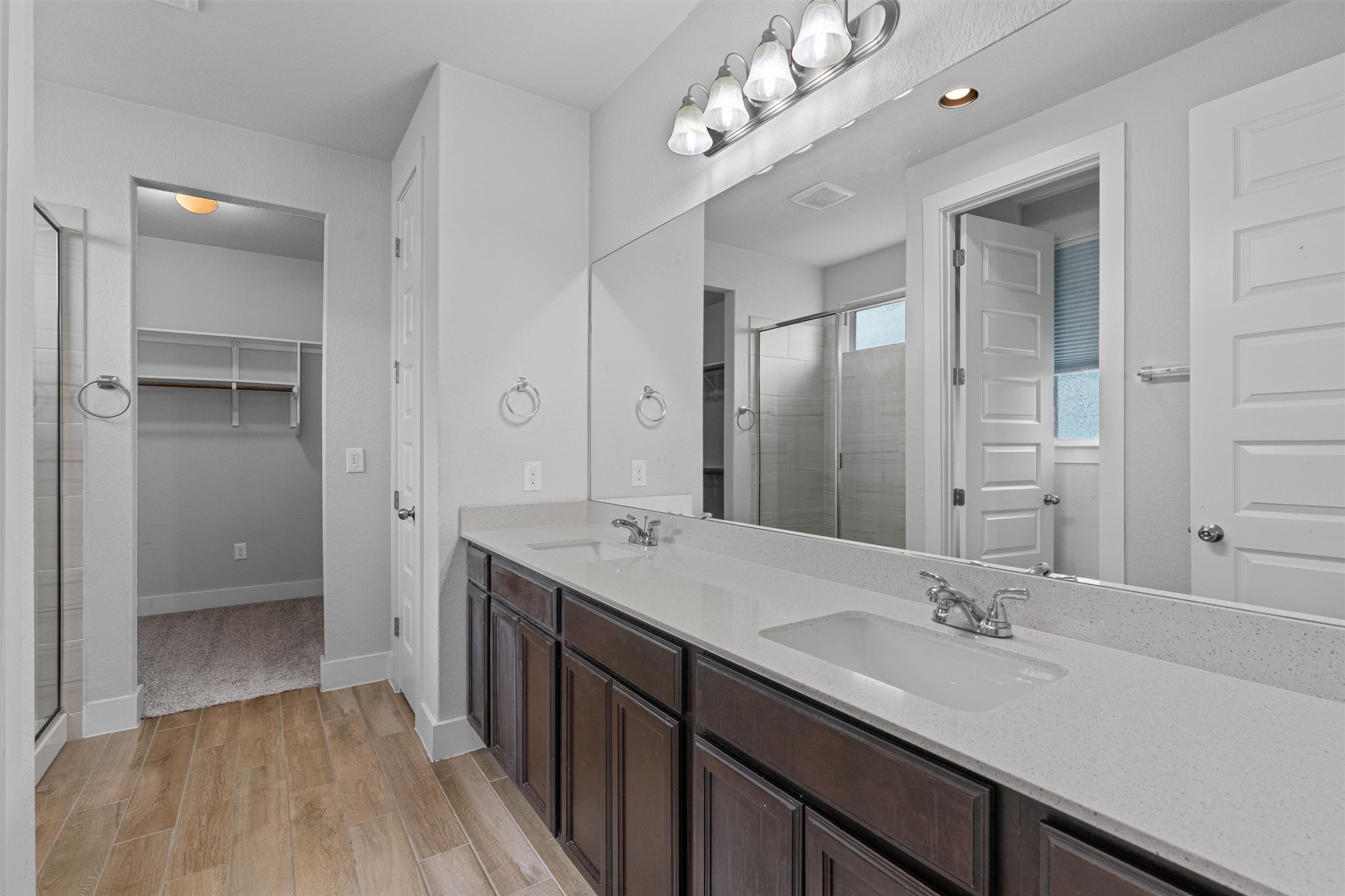 11217 Charger Way Manor, TX 78653 - Photo 16 of 35 Bathroom featuring a shower stall, a walk in closet, double vanity, and light wood-style flooring