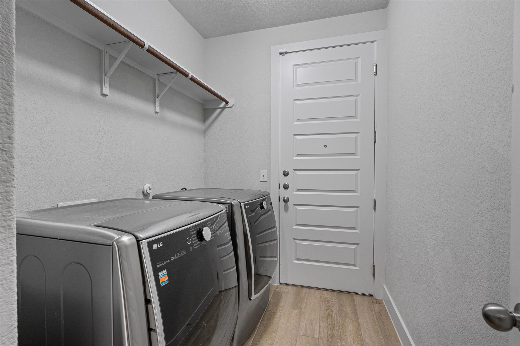 11217 Charger Way Manor, TX 78653 - Photo 19 of 35 Laundry area featuring a textured wall, light wood-style flooring, and separate washer and dryer