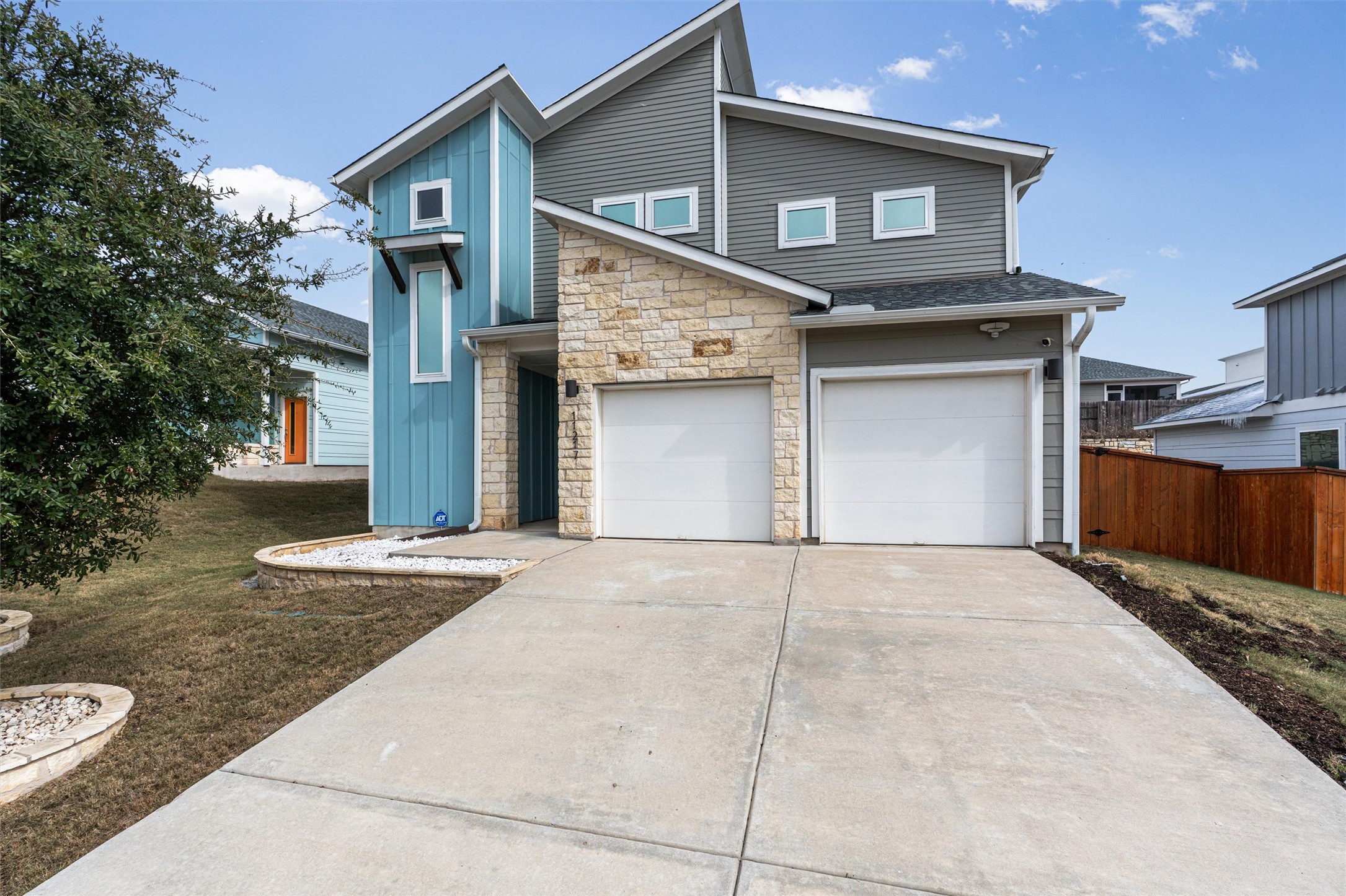 11217 Charger Way Manor, TX 78653 - Photo 2 of 35 View of front of house with stone siding, concrete driveway, an attached garage, and board and batten siding