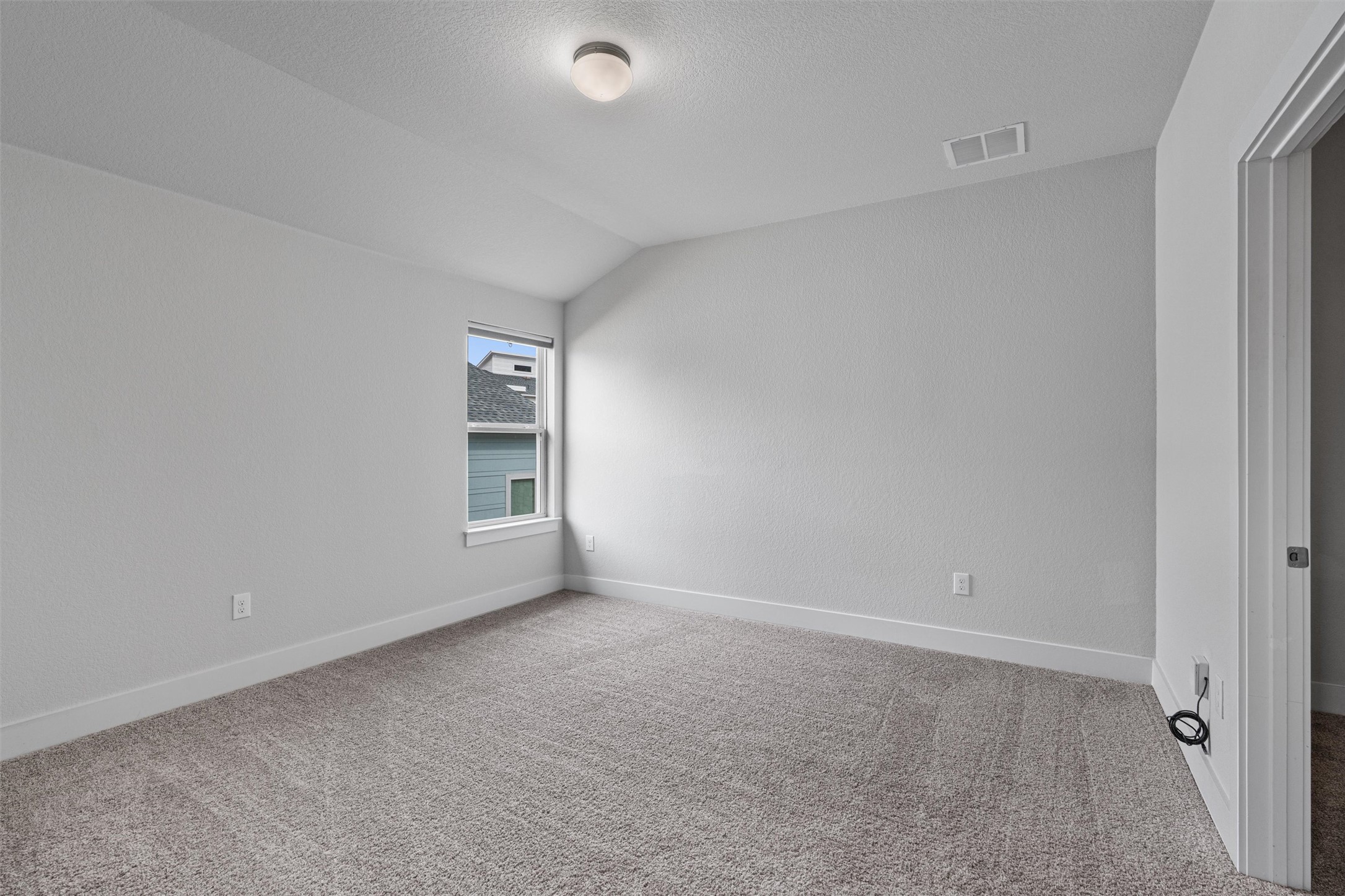 11217 Charger Way Manor, TX 78653 - Photo 24 of 35 Empty room with lofted ceiling, light colored carpet, and a textured ceiling