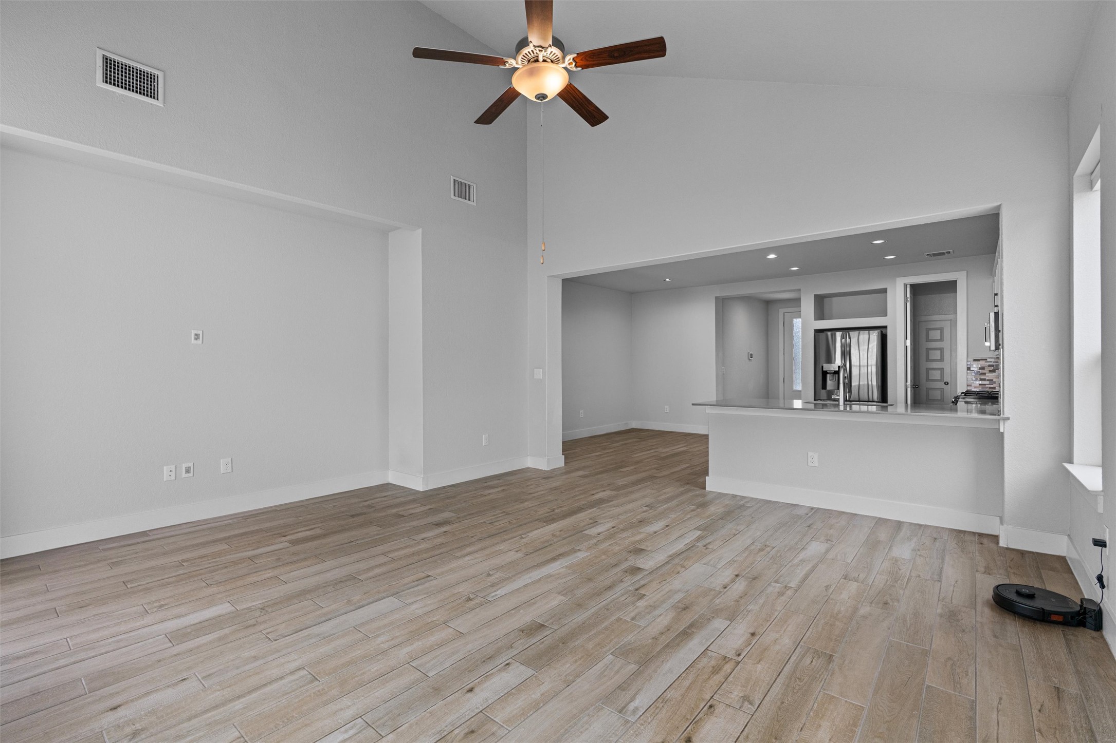 11217 Charger Way Manor, TX 78653 - Photo 4 of 35 Unfurnished living room featuring light wood-style floors, a ceiling fan, high vaulted ceiling, and recessed lighting