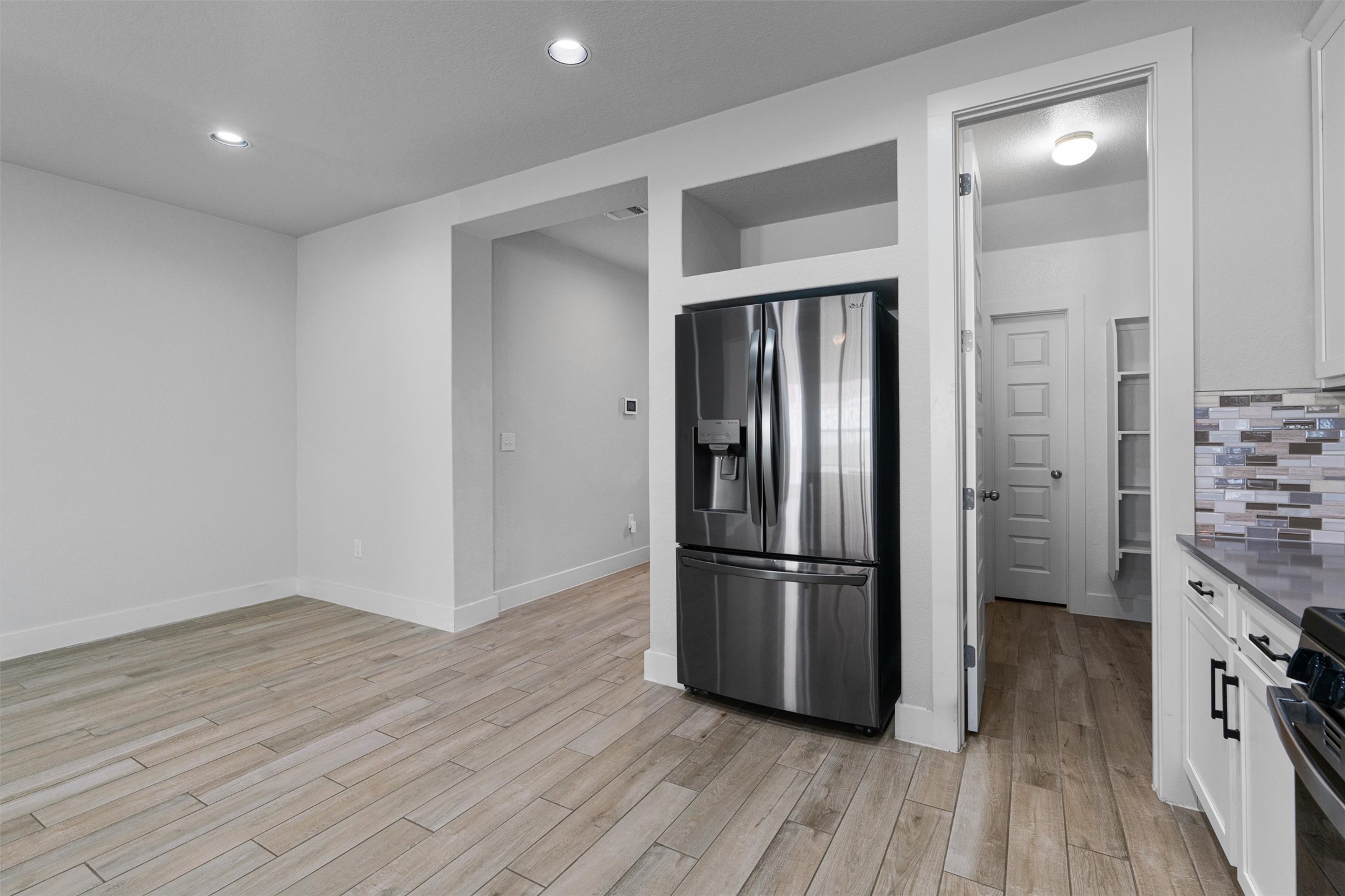 11217 Charger Way Manor, TX 78653 - Photo 7 of 35 Kitchen with stainless steel refrigerator with ice dispenser, white cabinets, stove, dark stone countertops, and light wood finished floors