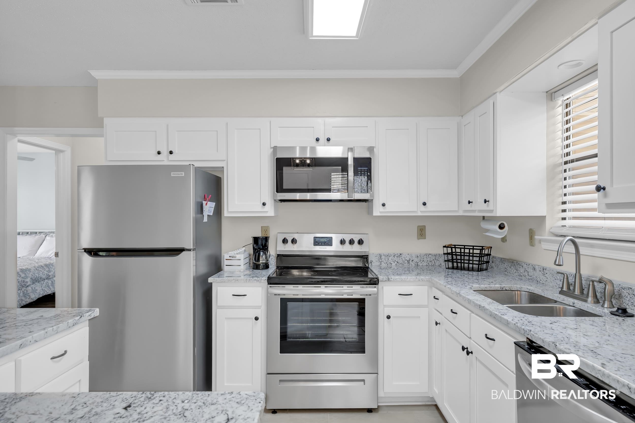 8081 Bryant's Lndg Road Stockton, AL 36579 - Photo 21 of 48 Kitchen featuring stainless steel appliances, white cabinetry, light stone counters, and ornamental molding