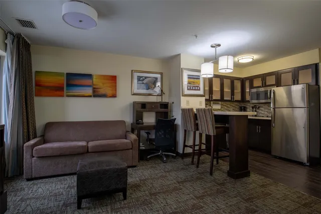 a living room with furniture and a dining table with kitchen appliances