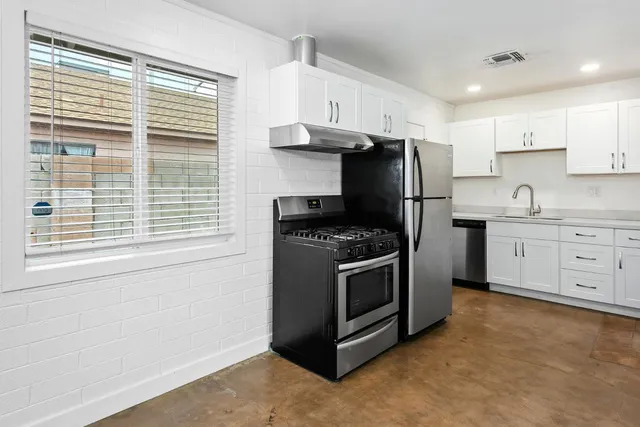 a kitchen with stainless steel appliances granite countertop a stove a sink and a refrigerator