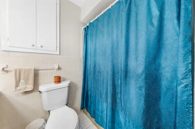 a white toilet sitting next to a wooden cabinet