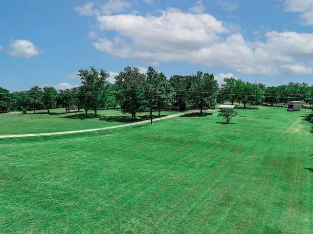 a view of a big yard with a house in the background