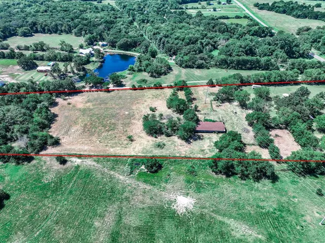 an aerial view of residential house with outdoor space and trees all around