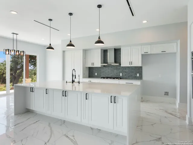 a kitchen with kitchen island granite countertop a sink a counter top space and cabinets