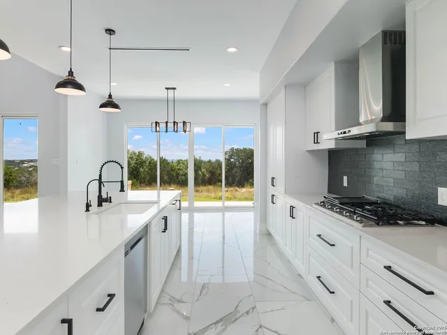 a kitchen with granite countertop a stove a sink a refrigerator and window