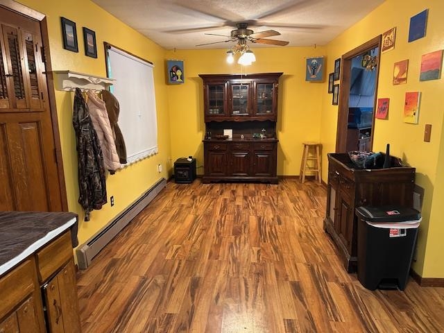38 Locust Drive Babbitt, MN 55706 - Photo 2 of 29 Dining room featuring a baseboard heating unit, ceiling fan, dark wood-style flooring, and baseboards