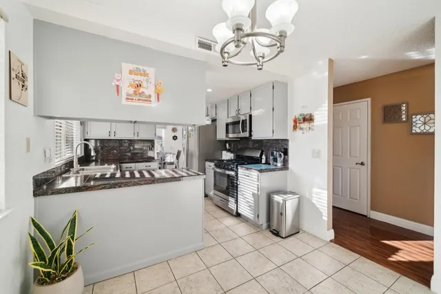 a kitchen with stainless steel appliances granite countertop a refrigerator a stove a sink dishwasher and white cabinets with wooden floor