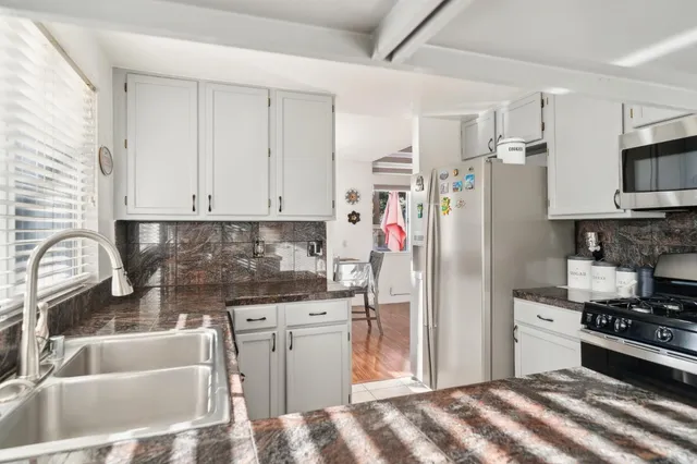 a kitchen with stainless steel appliances granite countertop a refrigerator sink and stove