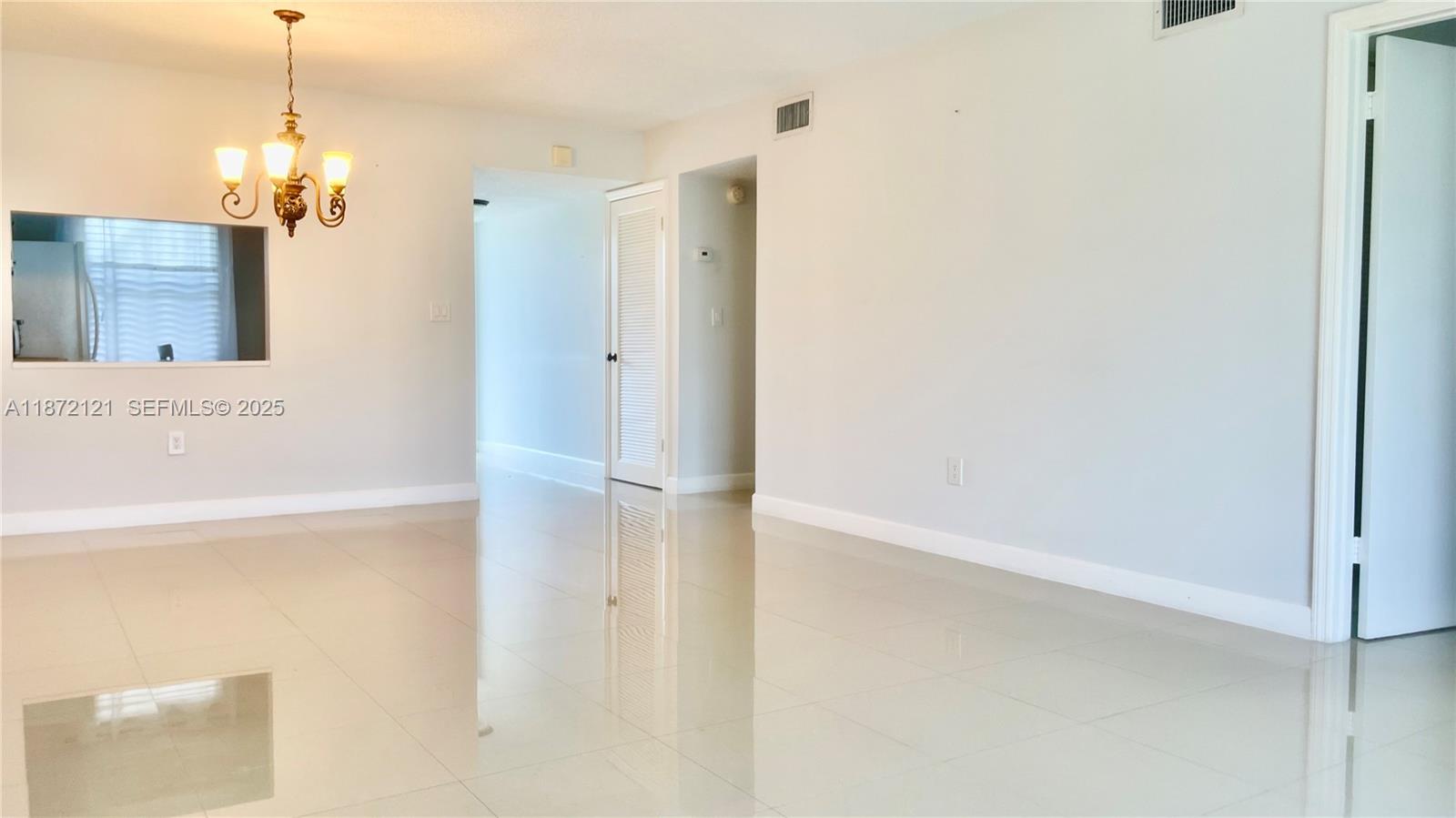 9856 Marina Boulevard, Unit 1320 Boca Raton, FL 33428 - Photo 23 of 48 a view of a hallway with a white refrigerator a table and chairs