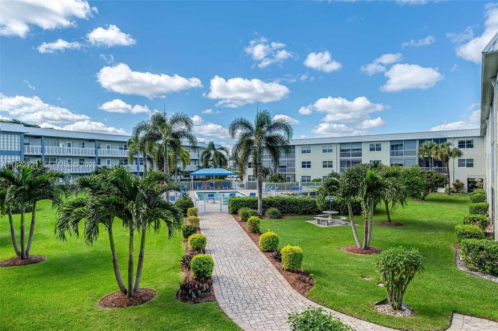 9856 Marina Boulevard, Unit 1320 Boca Raton, FL 33428 - Photo 6 of 48 a view of a white house with a big yard and potted plants