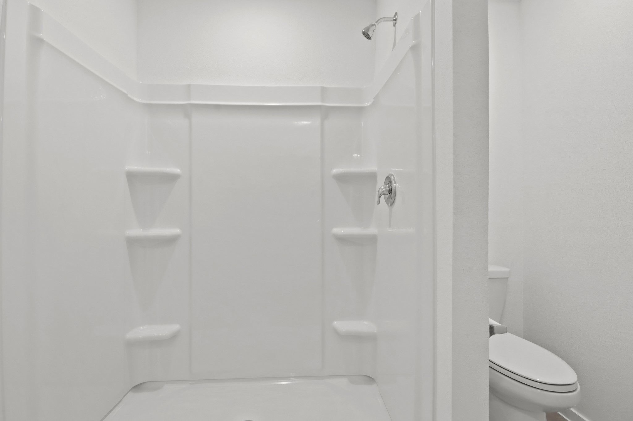 18779 Ribolla Drive New Caney, TX 77357 - Photo 13 of 24 Bright and modern bathroom featuring a pristine white shower with built-in shelving and a sleek toilet.