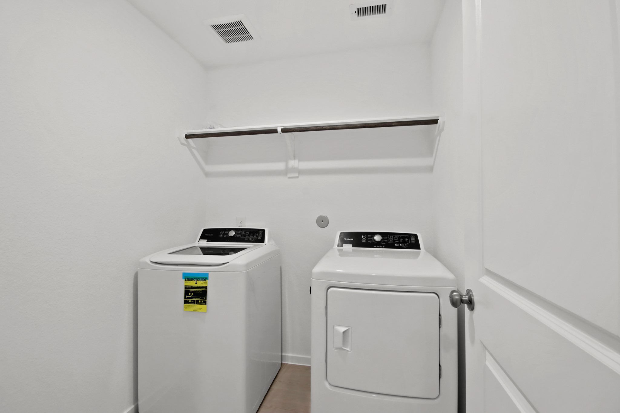 18779 Ribolla Drive New Caney, TX 77357 - Photo 14 of 24 This photo shows a compact laundry room with a washer and dryer, a white interior, and a shelf above for storage.