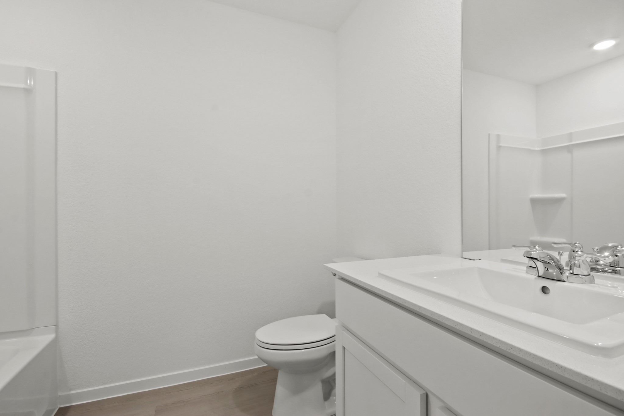 18779 Ribolla Drive New Caney, TX 77357 - Photo 18 of 24 This is a modern, bright bathroom featuring a sleek white vanity with a built-in sink, a toilet, and a shower with a clean, minimalist design.