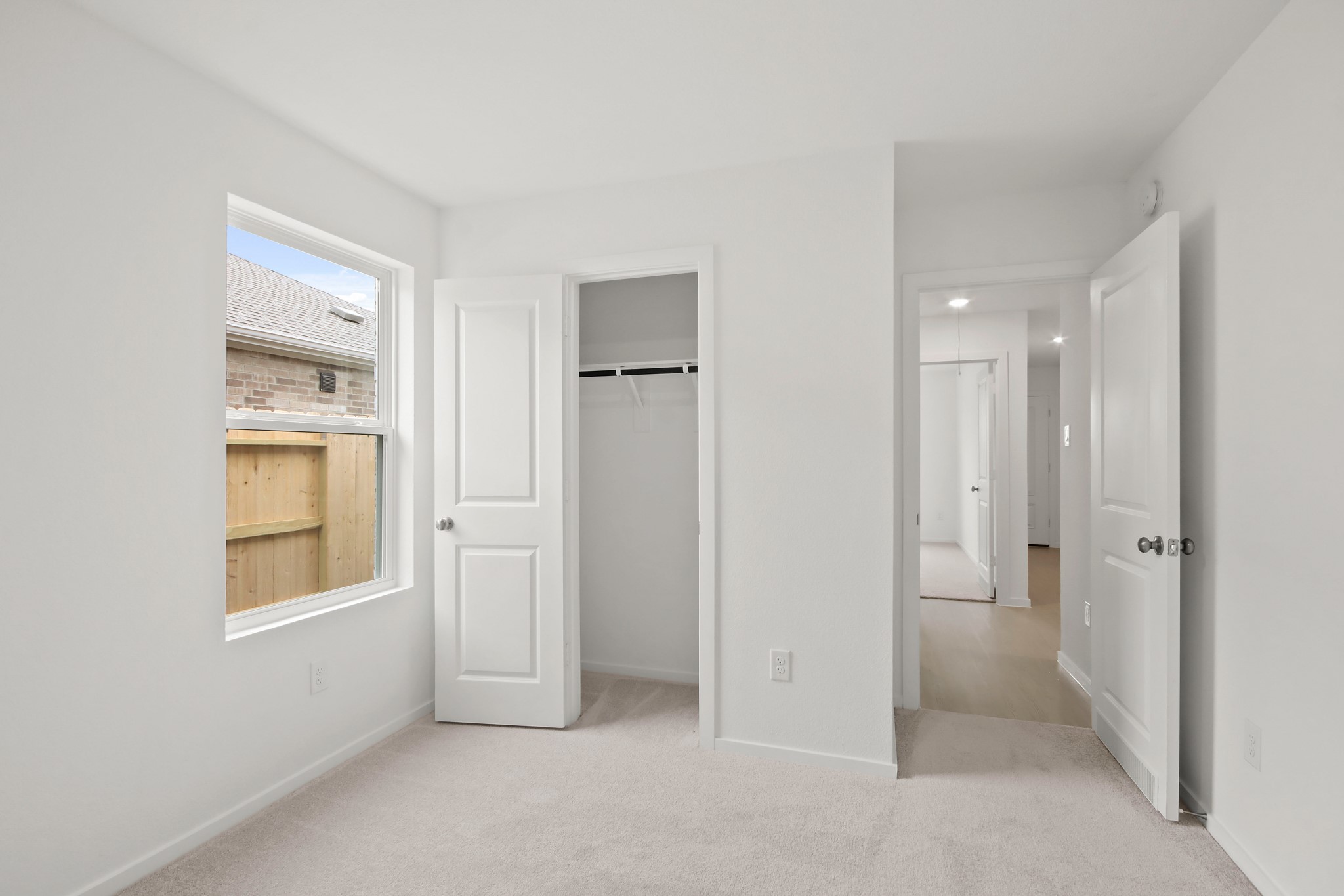 18779 Ribolla Drive New Caney, TX 77357 - Photo 20 of 24 This is a bright bedroom with a window, closet, and light walls and carpet. It offers a cozy space with direct access to a hallway.