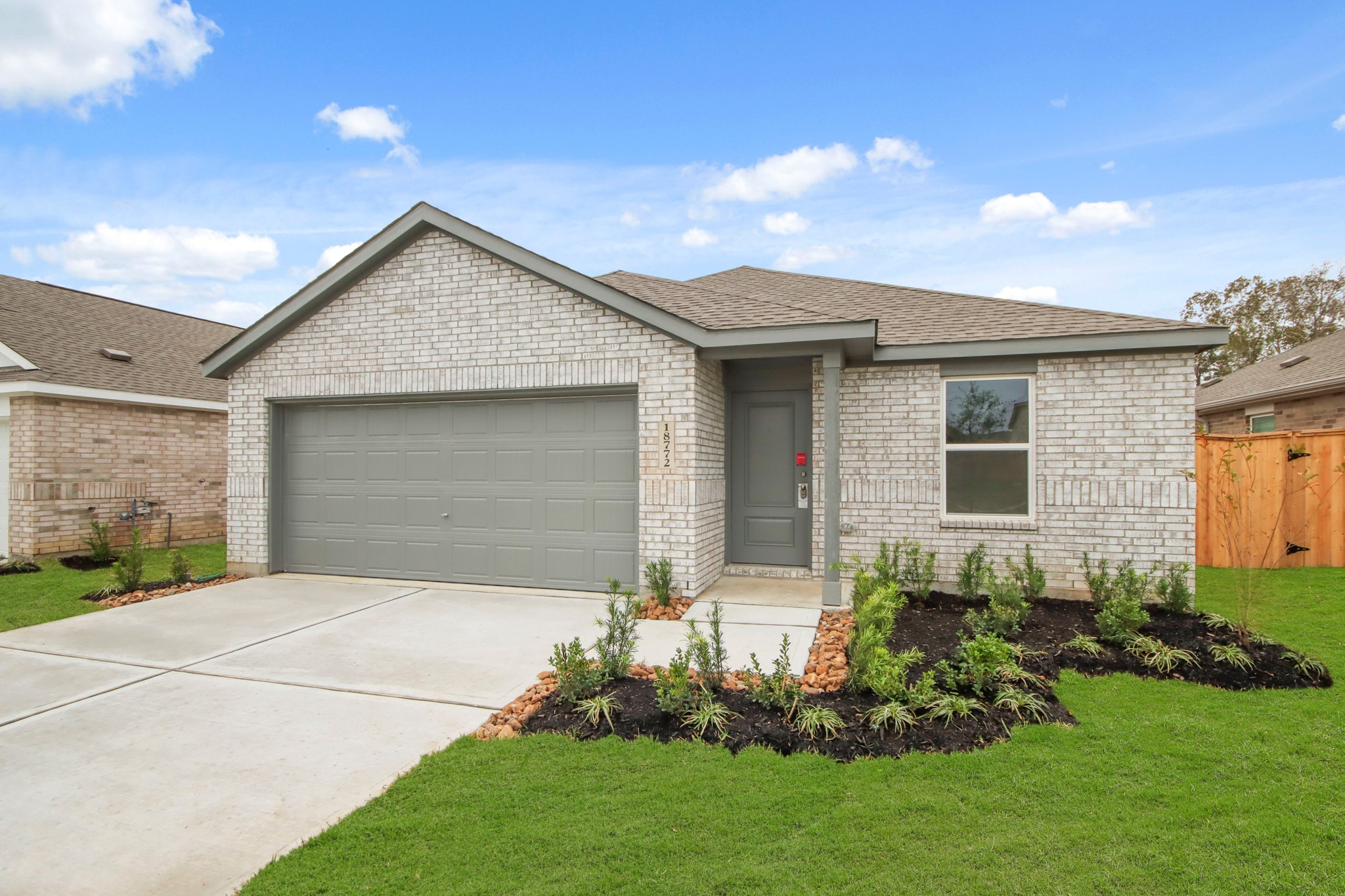 18779 Ribolla Drive New Caney, TX 77357 - Photo 2 of 24 Charming single-story home with a modern brick exterior, featuring a two-car garage. The front yard is landscaped with fresh greenery, and the property includes a cozy entrywa.