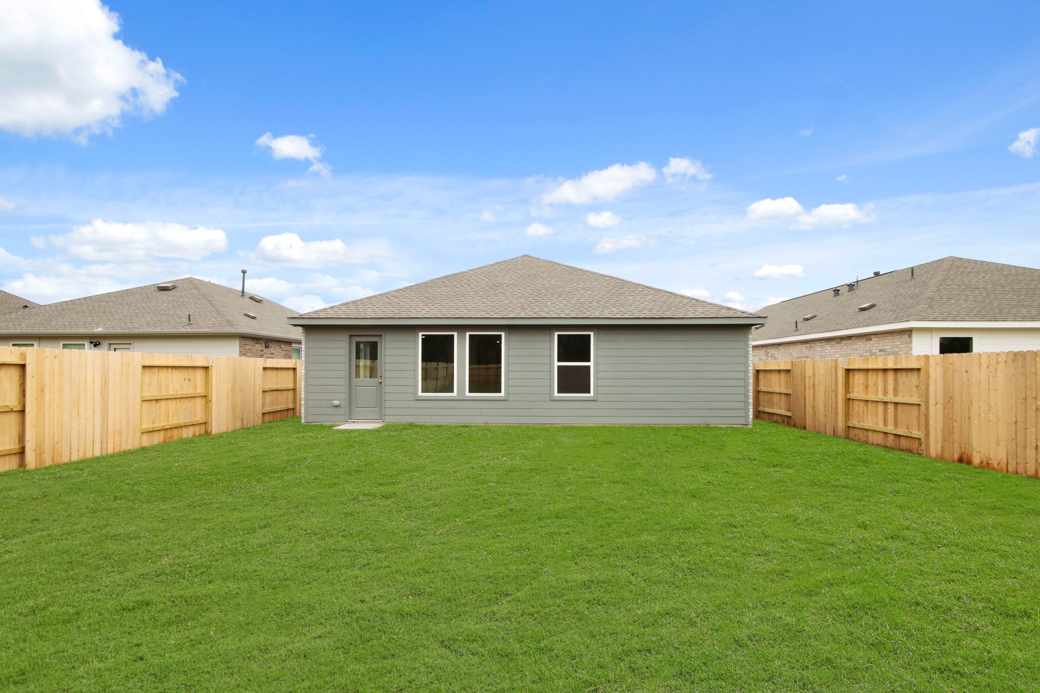 18779 Ribolla Drive New Caney, TX 77357 - Photo 23 of 24 Single-story home with a light exterior and a fenced backyard. The yard is spacious and grassy, ideal for outdoor activities.