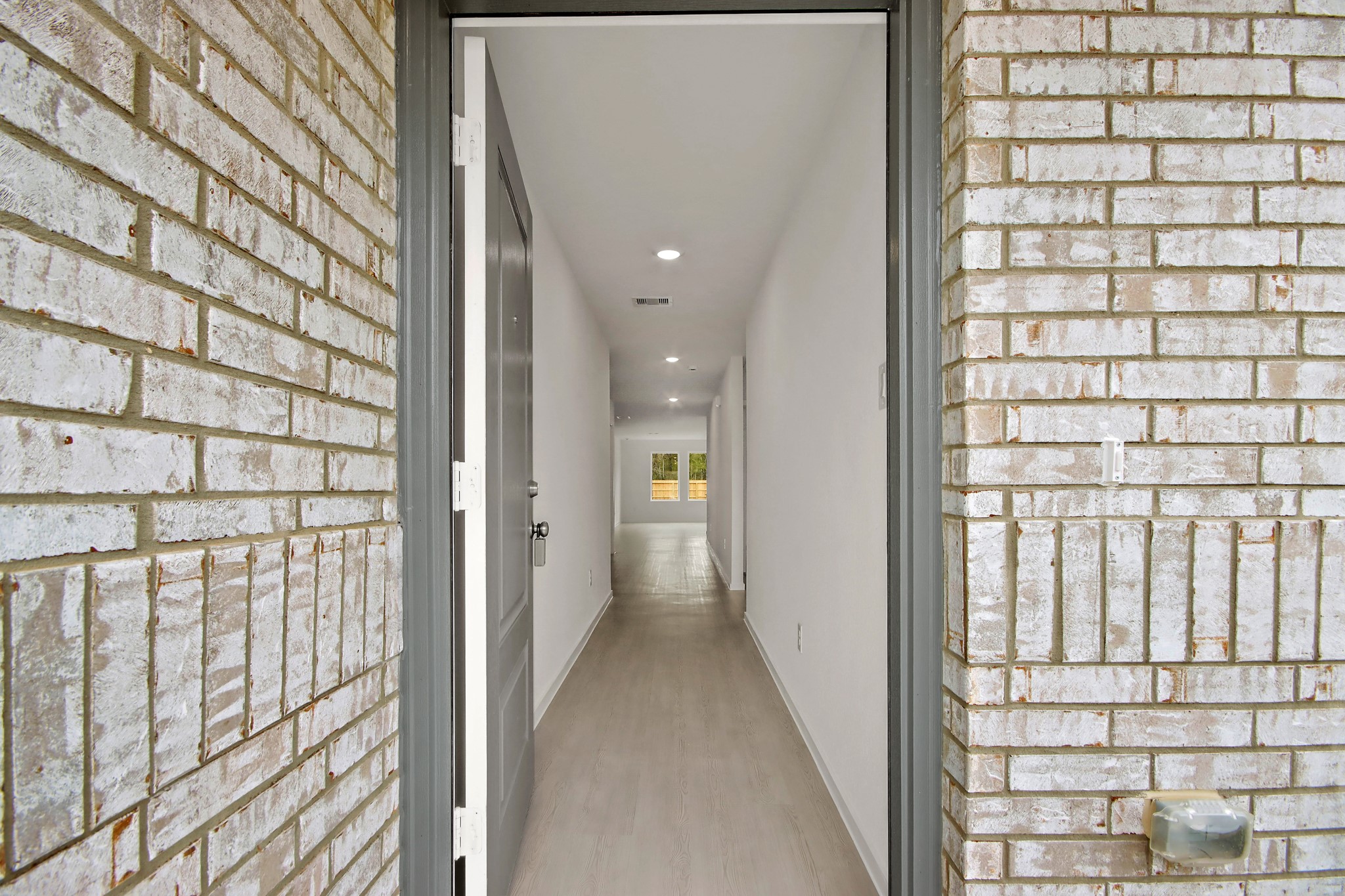 18779 Ribolla Drive New Caney, TX 77357 - Photo 3 of 24 Enjoy the welcoming entryway with light wood flooring and white walls, leading to a bright interior space. The brick exterior adds charm and character.