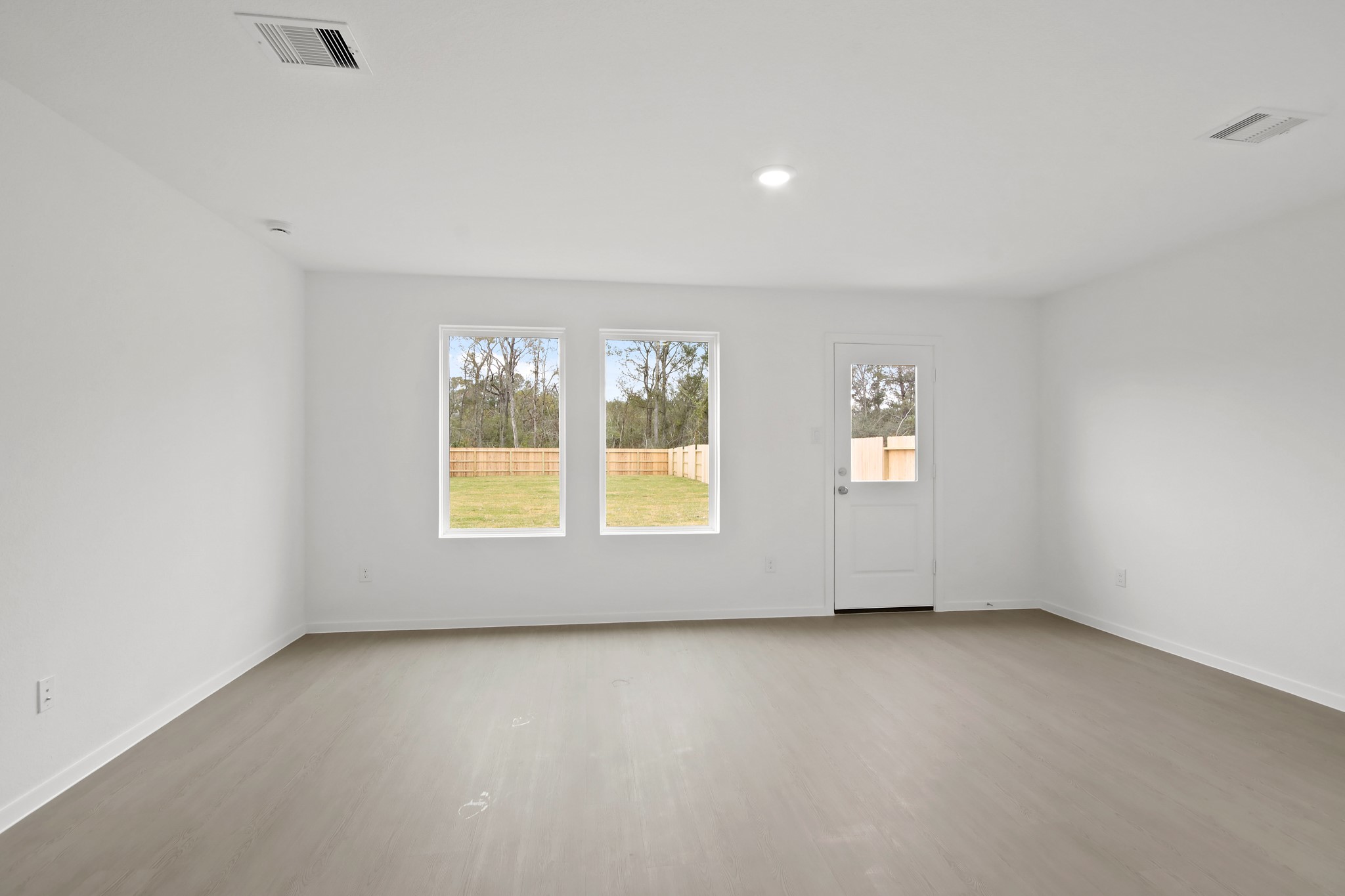 18779 Ribolla Drive New Caney, TX 77357 - Photo 4 of 24 Bright, spacious room with light-colored flooring, white walls, and large windows overlooking a fenced backyard. Includes a door leading outside.