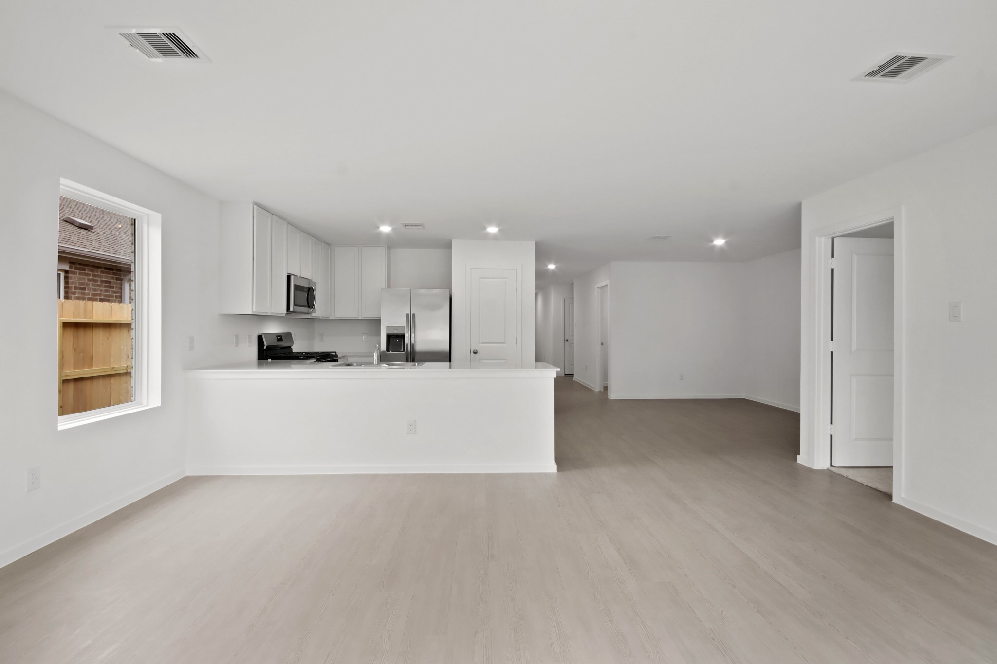 18779 Ribolla Drive New Caney, TX 77357 - Photo 5 of 24 This photo showcases a bright, open-concept living space with modern finishes. The kitchen features sleek stainless steel appliances and white cabinetry, while the living area has light wood flooring and ample natural light.