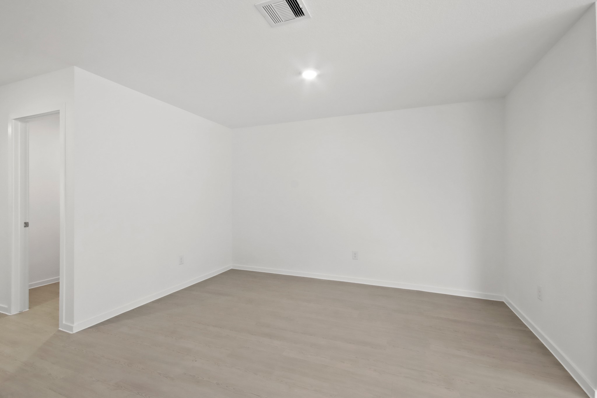 18779 Ribolla Drive New Caney, TX 77357 - Photo 6 of 24 This photo shows a bright, empty room with white walls and light wood flooring. It features a recessed ceiling light and an open doorway leading to another area. Ideal for customization.
