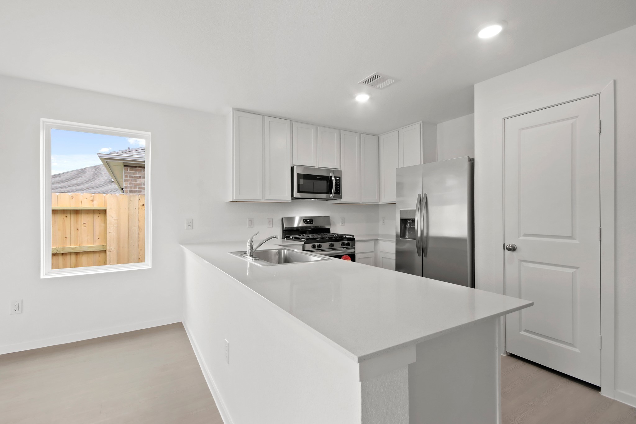 18779 Ribolla Drive New Caney, TX 77357 - Photo 7 of 24 Modern kitchen with white cabinetry, stainless steel appliances, and a sleek island. Bright and airy with a window overlooking the backyard.