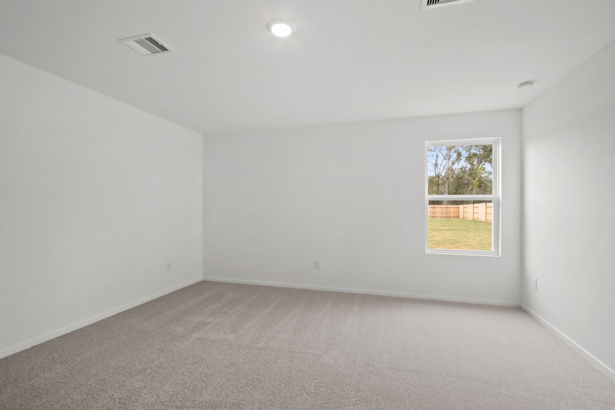 18779 Ribolla Drive New Caney, TX 77357 - Photo 10 of 24 This photo showcases a bright, unfurnished room with neutral carpet and walls, featuring a single window that allows natural light and overlooks a fenced backyard.