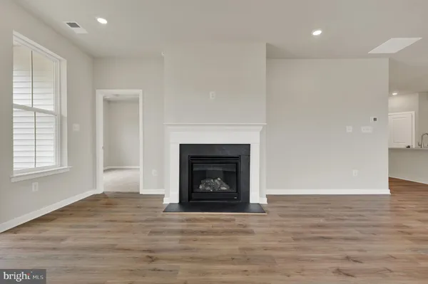 a view of an empty room with wooden floor and a fireplace