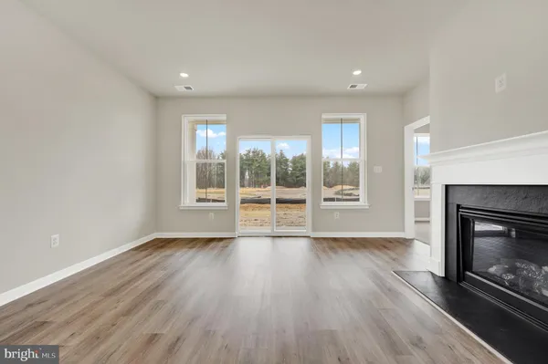 an empty room with wooden floor fireplace and windows
