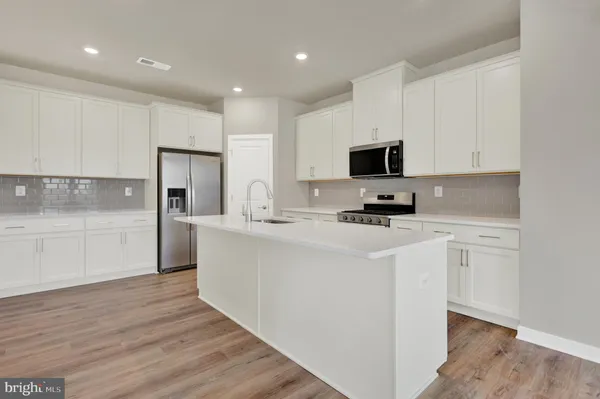 a kitchen with stainless steel appliances a refrigerator sink and white cabinets