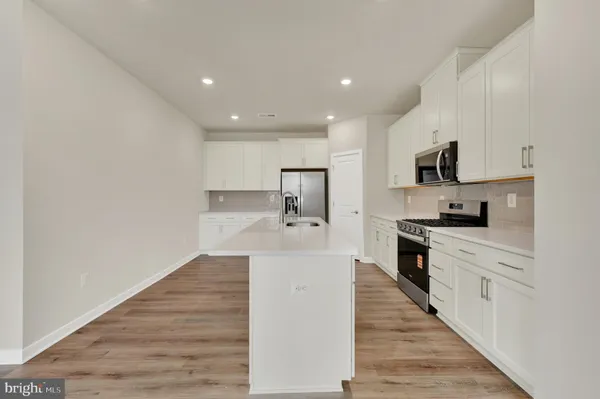 a large white kitchen with wooden floor and a sink