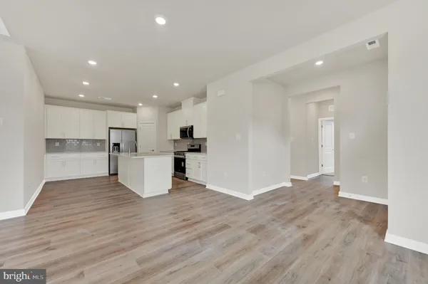 a view of kitchen with kitchen island wooden floors appliances and cabinets