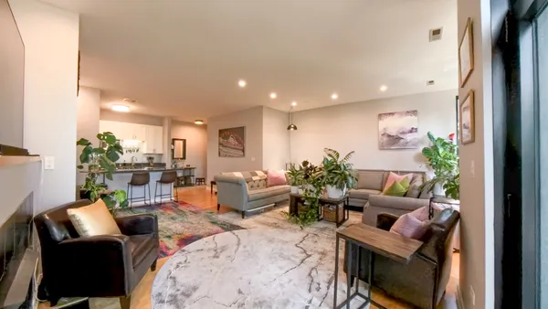 a living room with furniture a potted plant and a large window