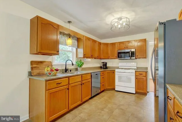 a kitchen with stainless steel appliances granite countertop a sink dishwasher stove and refrigerator