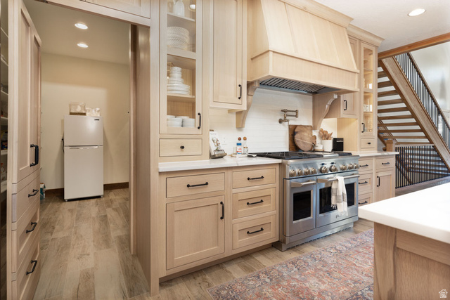 382 Ridgeview Street, Unit 8 & 9 Brian Head, UT 84719 - Photo 12 of 52 Gourmet kitchen featuring a professional-grade range, custom wood cabinetry, a built-in wood range hood, light-toned countertops, and a full-height tile backsplash