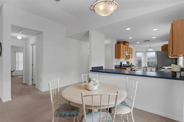a kitchen with stainless steel appliances a dining table chairs and a refrigerator