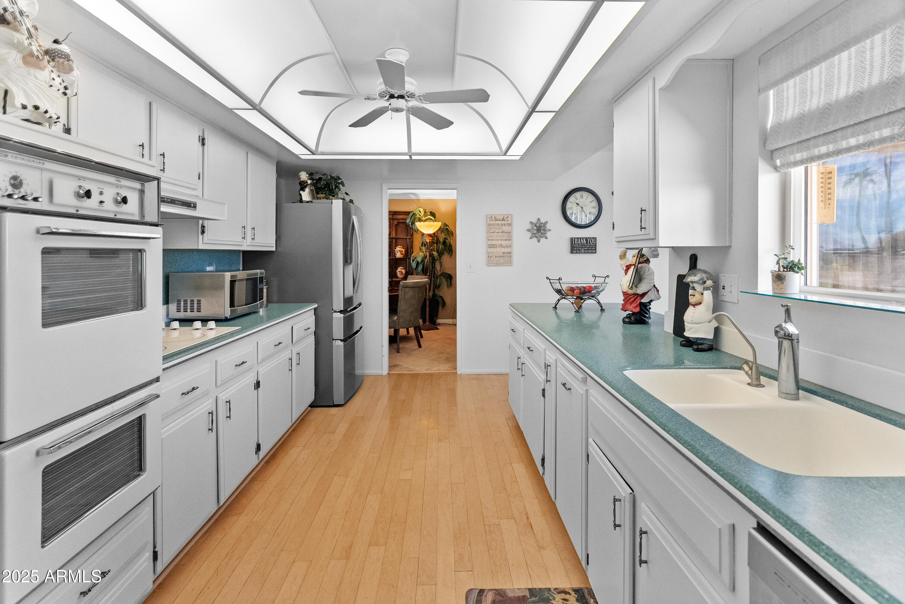 10229 West Bolivar Drive Sun City, AZ 85351 - Photo 7 of 54 a large white kitchen with stainless steel appliances granite countertop a lot of counter space and wooden floors