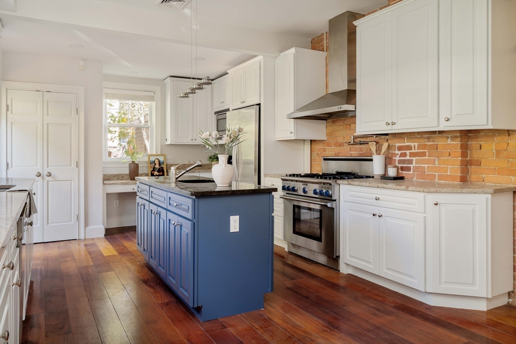 32 Hall Avenue, Unit 32 Somerville, MA 02144 - Photo 5 of 30 a kitchen with stainless steel appliances granite countertop a stove a sink dishwasher a refrigerator and white cabinets with wooden floor